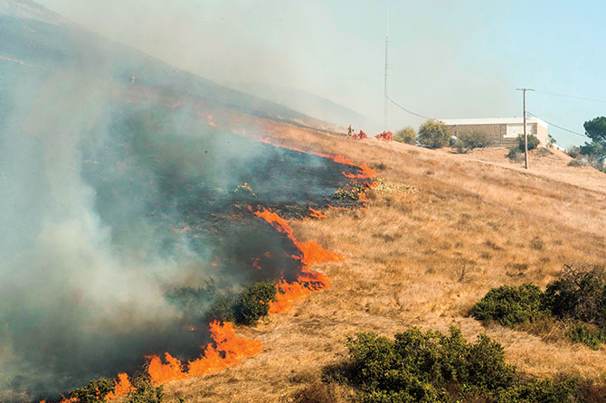 enlargeable photo of a fire raging in a field outside of a building