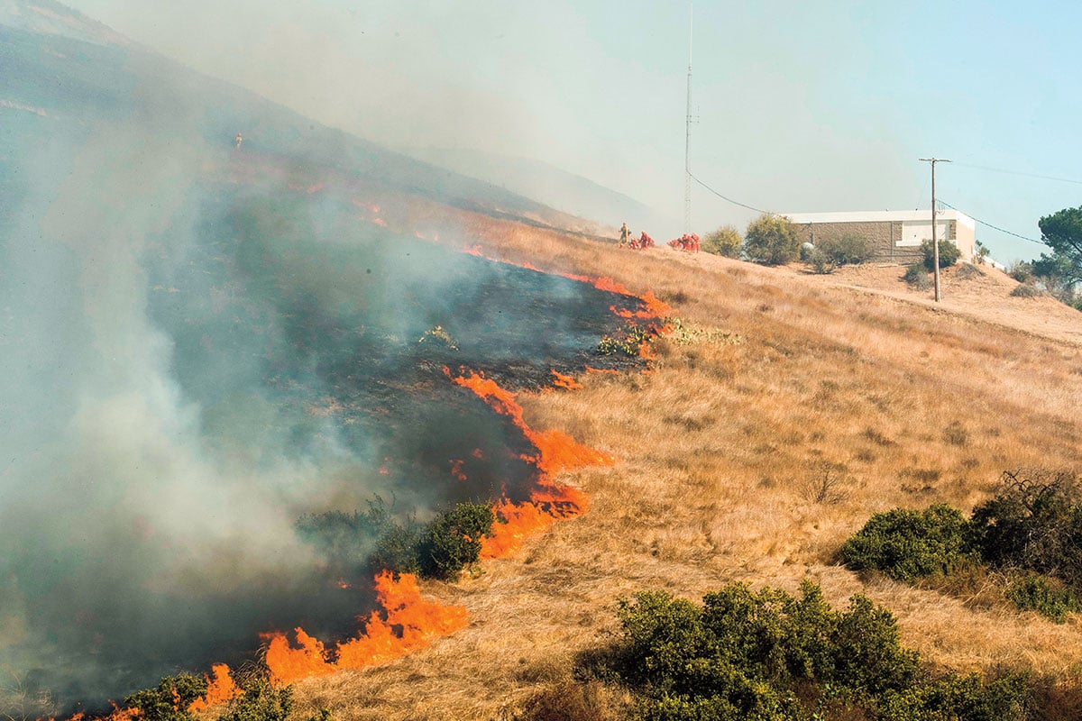 a fire raging in a field outside of a building