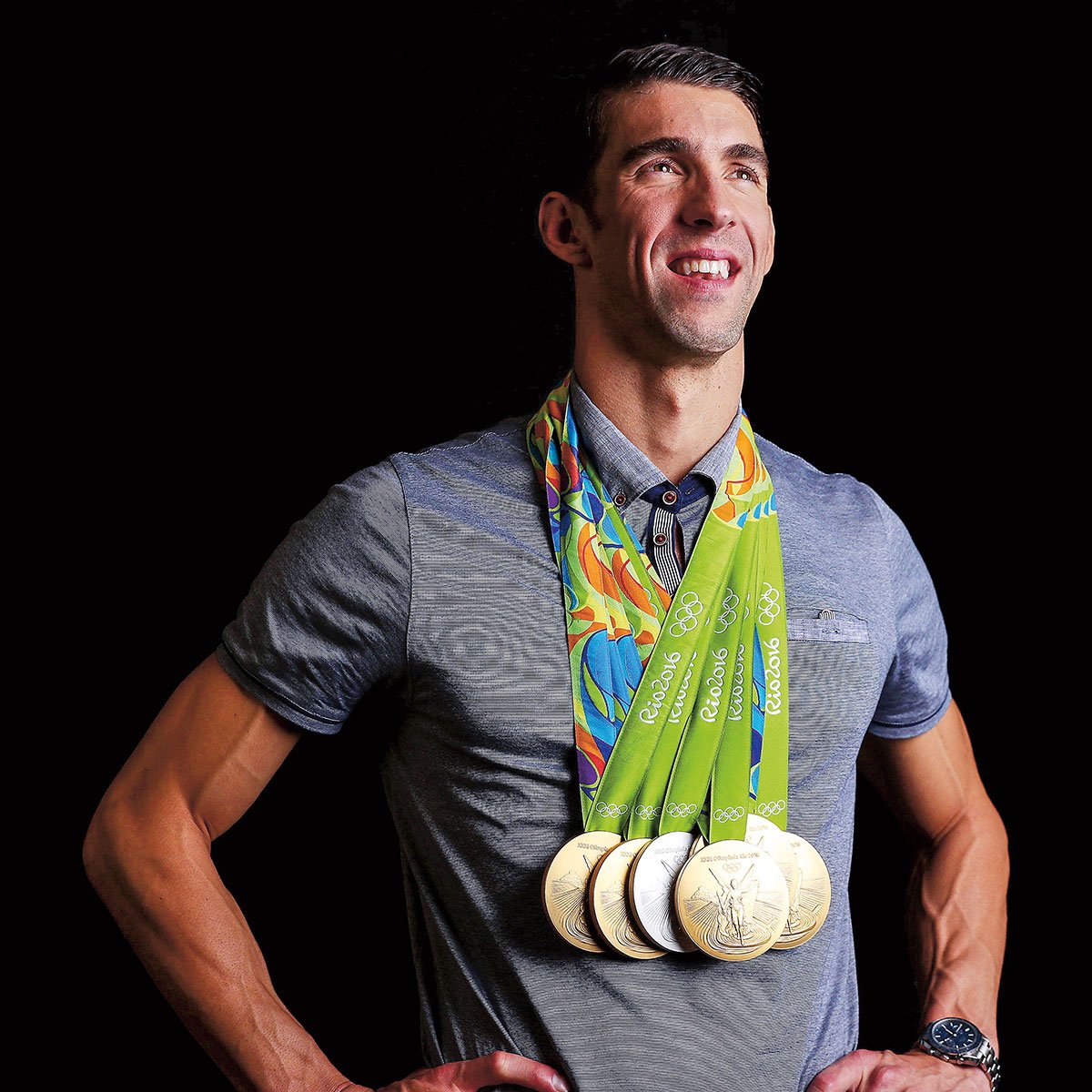 a man smiling and wearing multiple Olympic medals