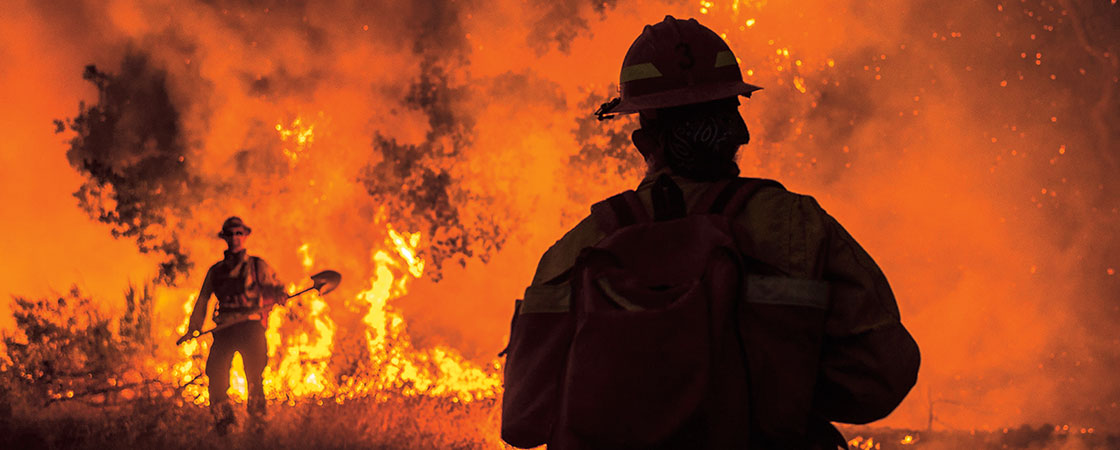 a firefighter standing in front of a large orange fire