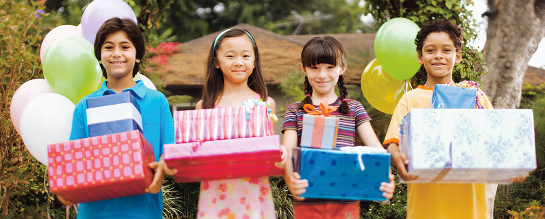 Four children holding presents as balloons float behind them